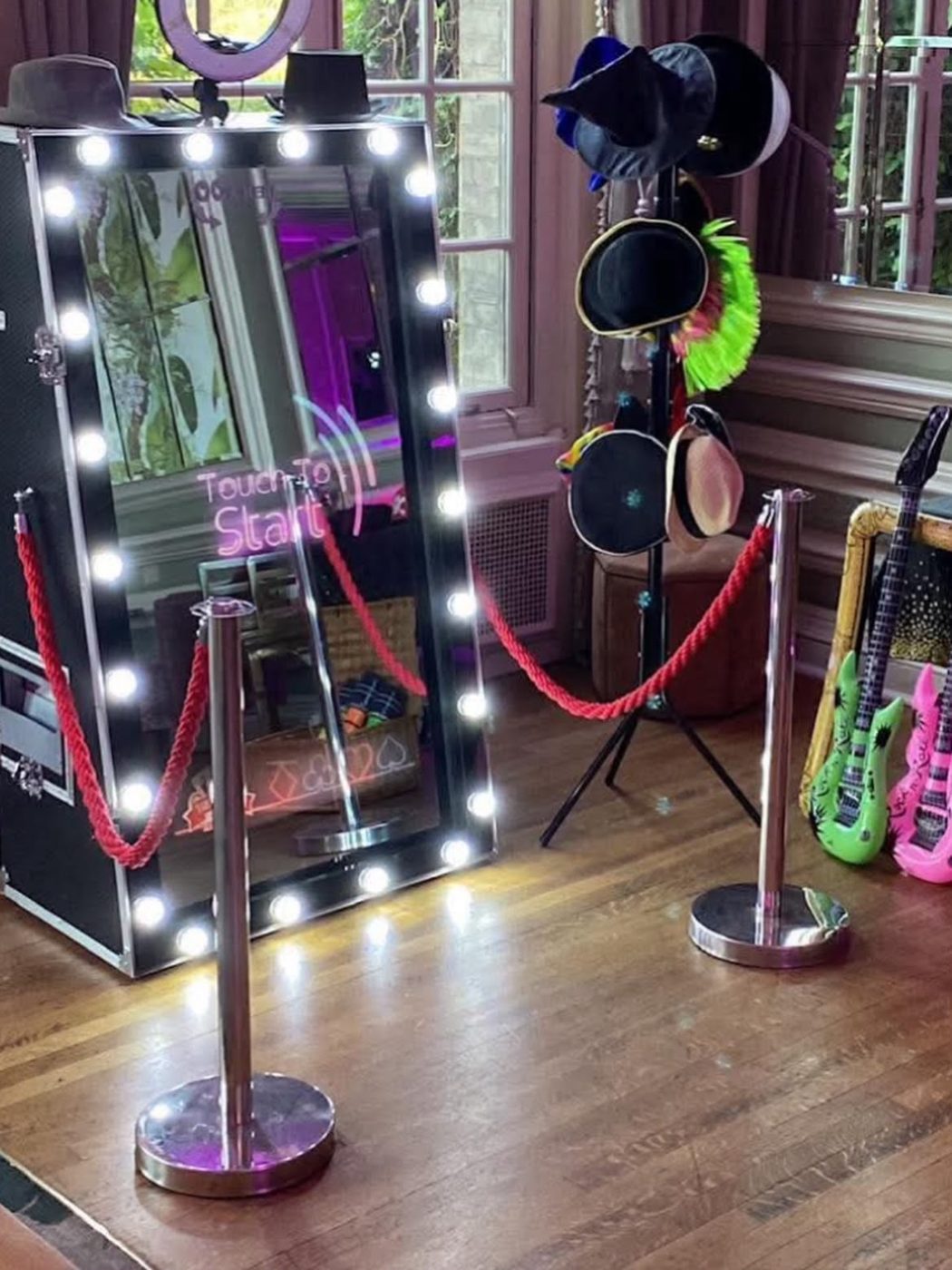 Magic Mirror photo booth with Hollywood bulbs, red carpet and rope barriers in an elegant venue room